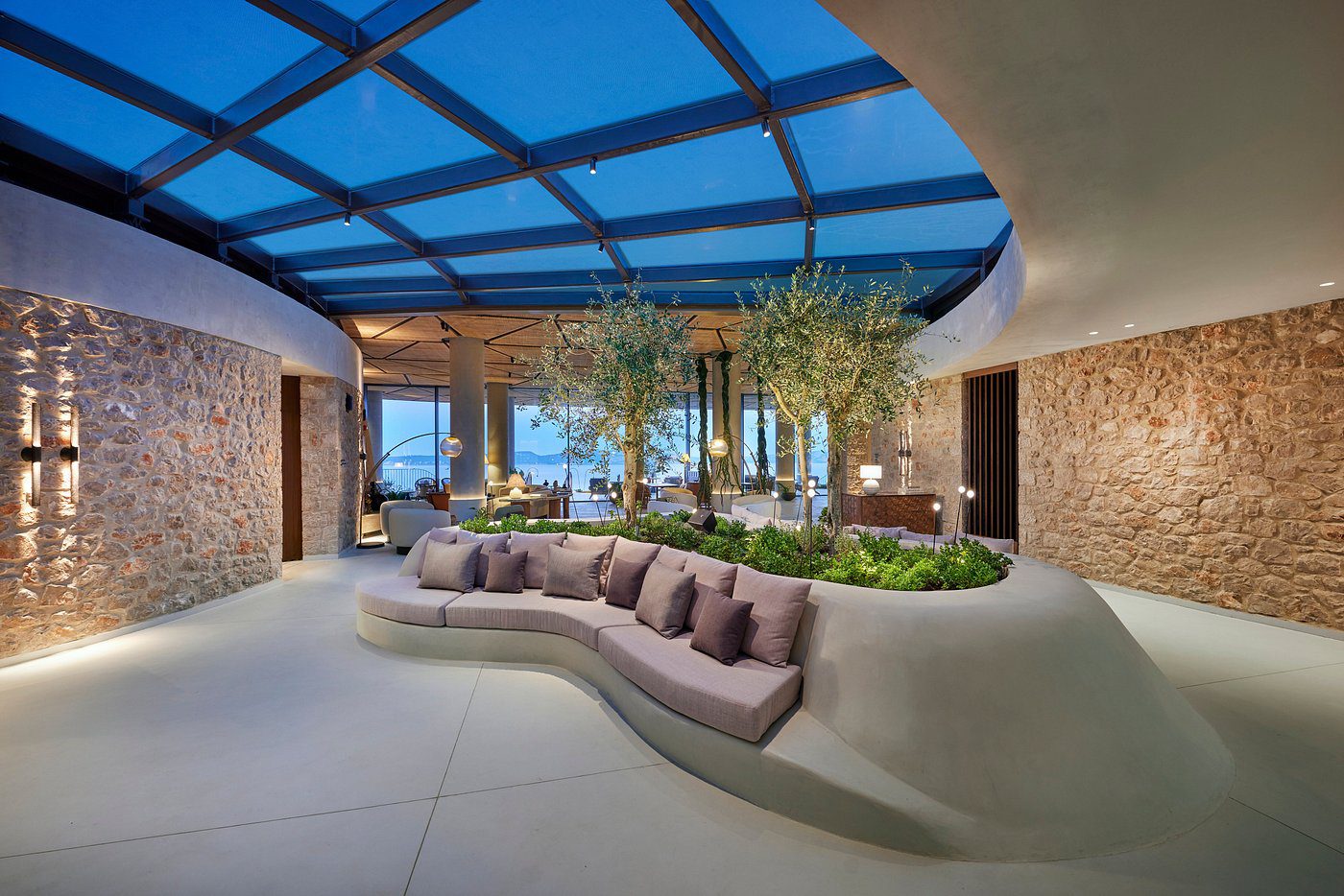 Modern outdoor lounge with curved seating under a transparent roof.