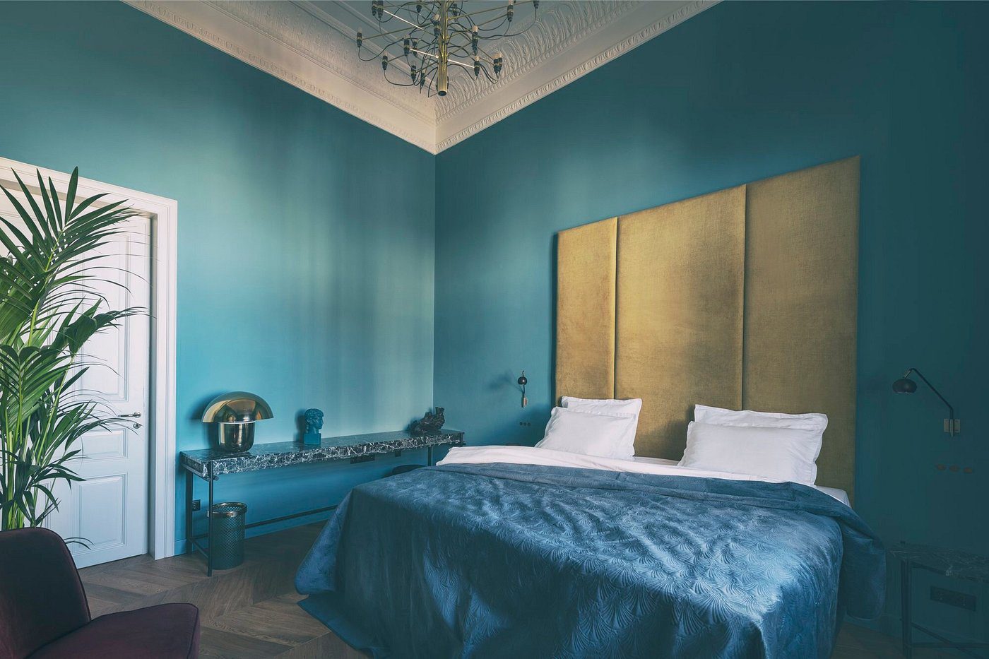 Elegant bedroom with teal walls and a gold-accented bed.