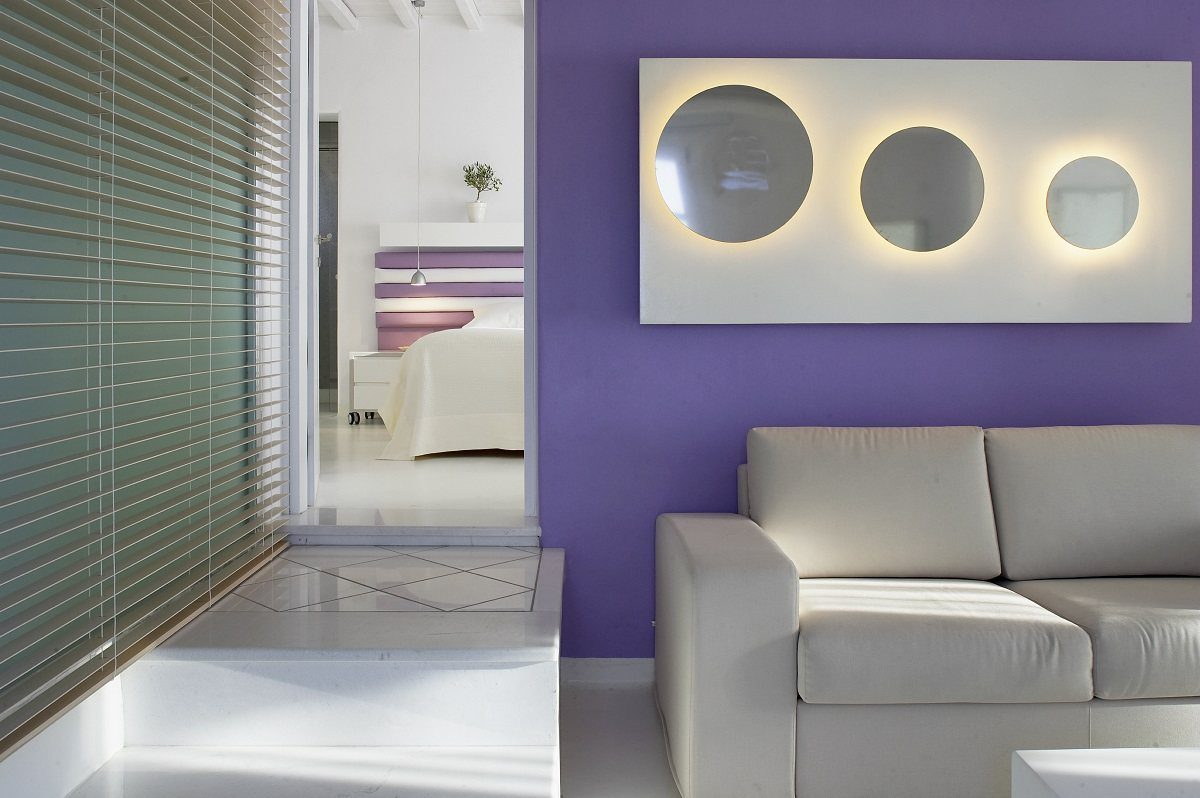 Modern living room with purple wall and illuminated circular art.