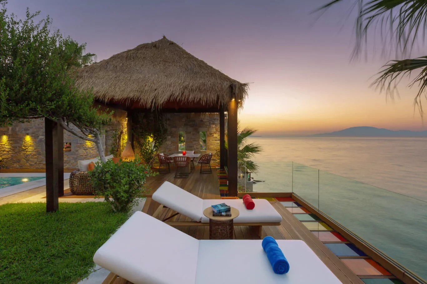 Tropical outdoor lounge with sunbeds at sunset by the water.