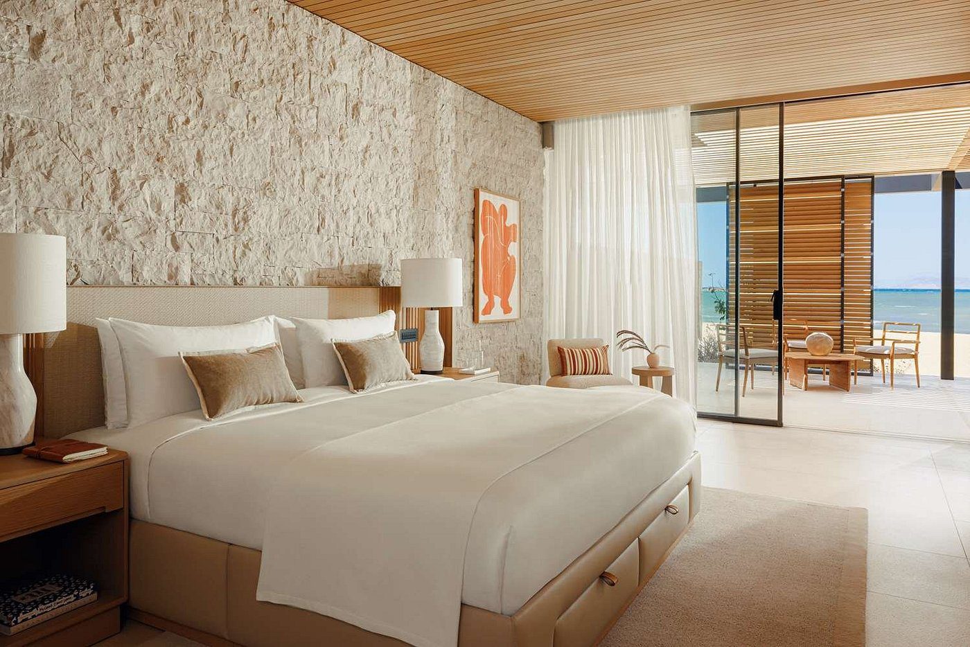 Serene bedroom with stone wall and large window overlooking a balcony.