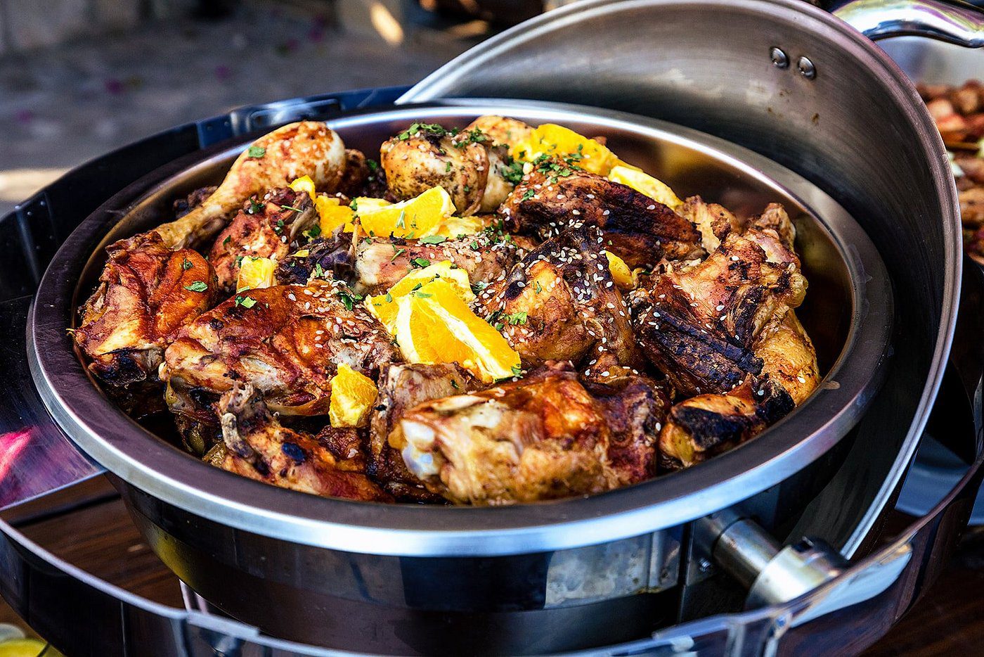 A bowl of grilled chicken garnished with orange slices and herbs.