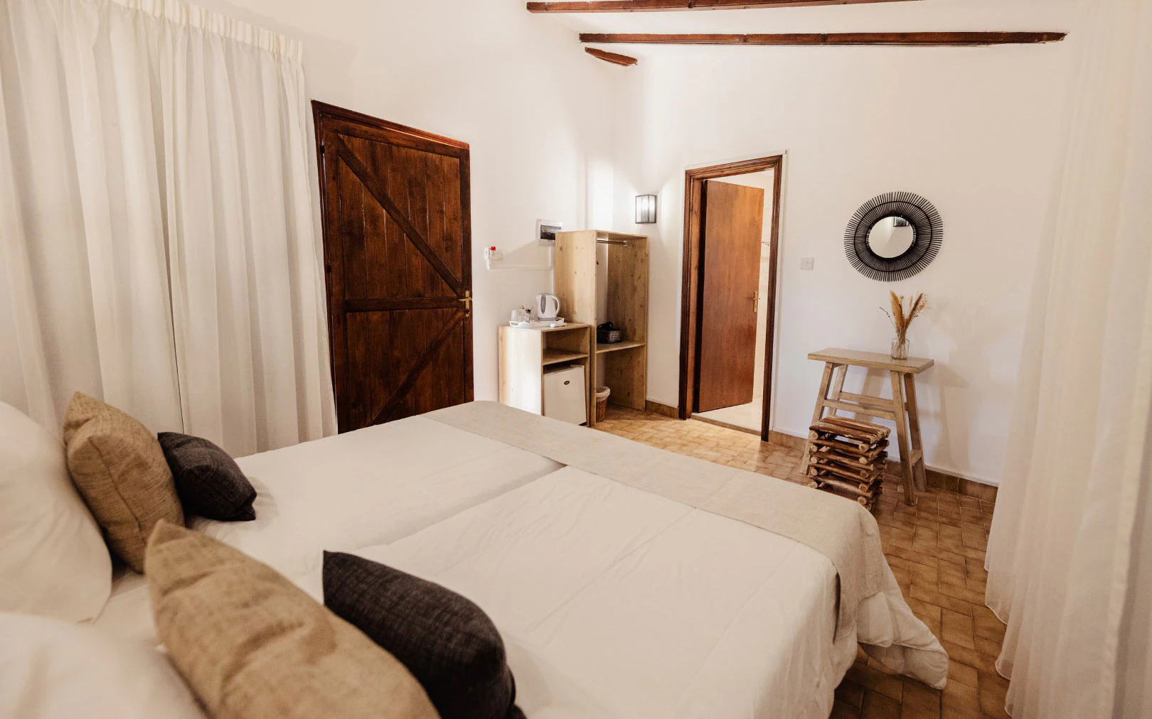 Cozy bedroom with twin beds, rustic wooden beams, and warm lighting.