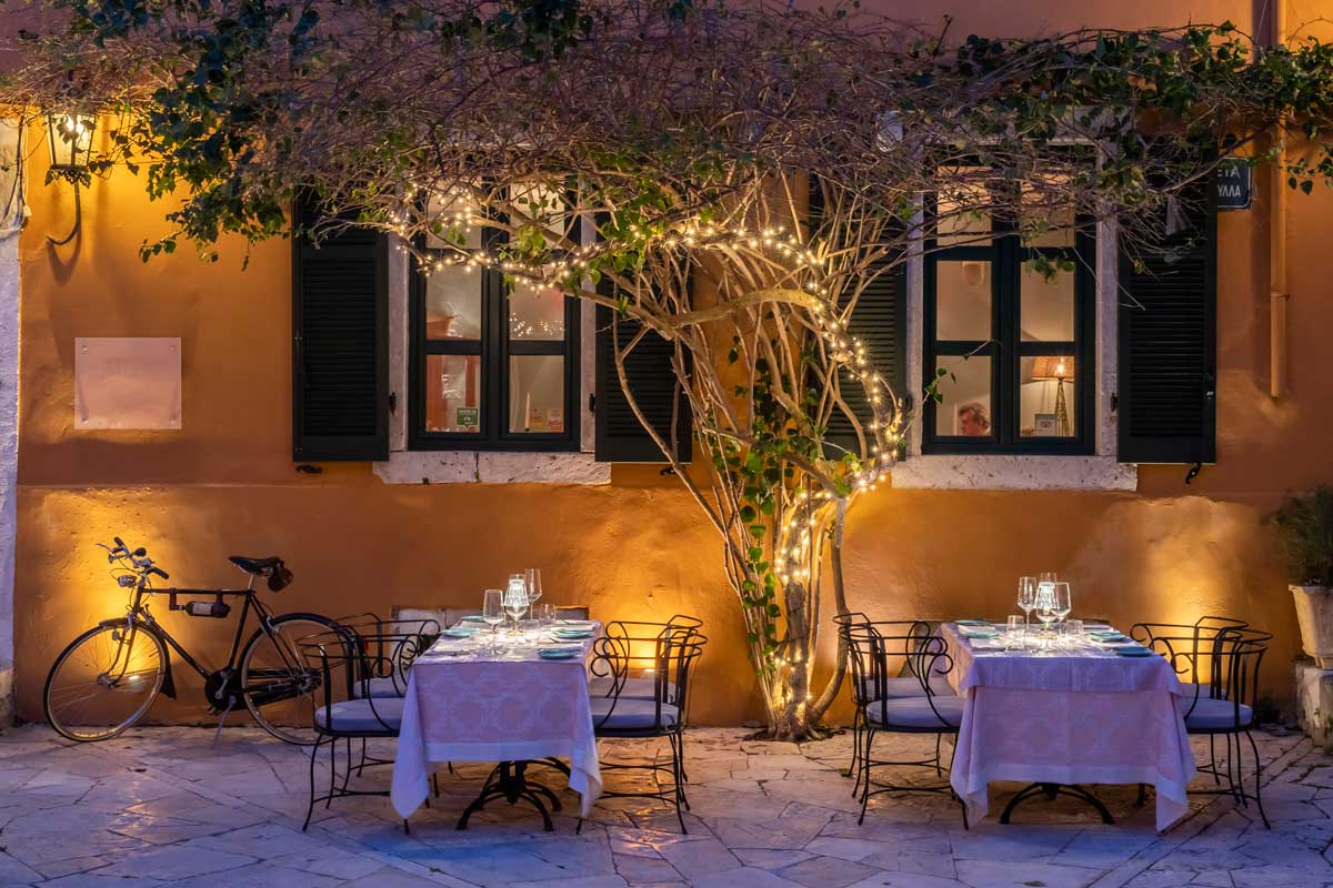 Cozy outdoor dining under a tree with warm lights at night.