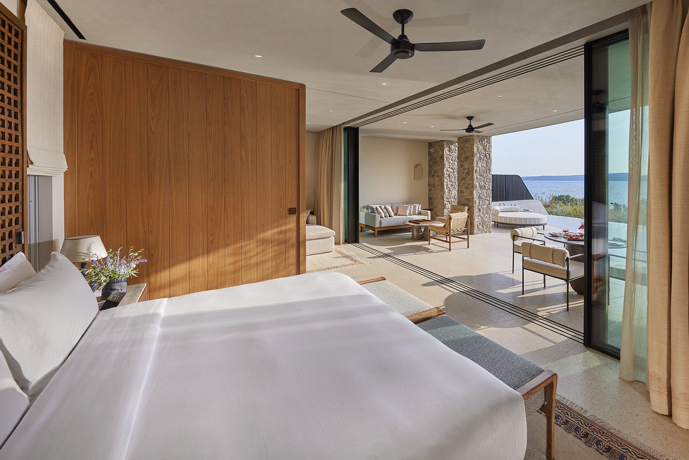 Modern bedroom with wooden accents and ocean view balcony.