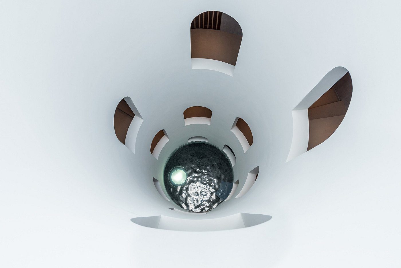 Top-down view of a spiral staircase with white walls and wooden railings.