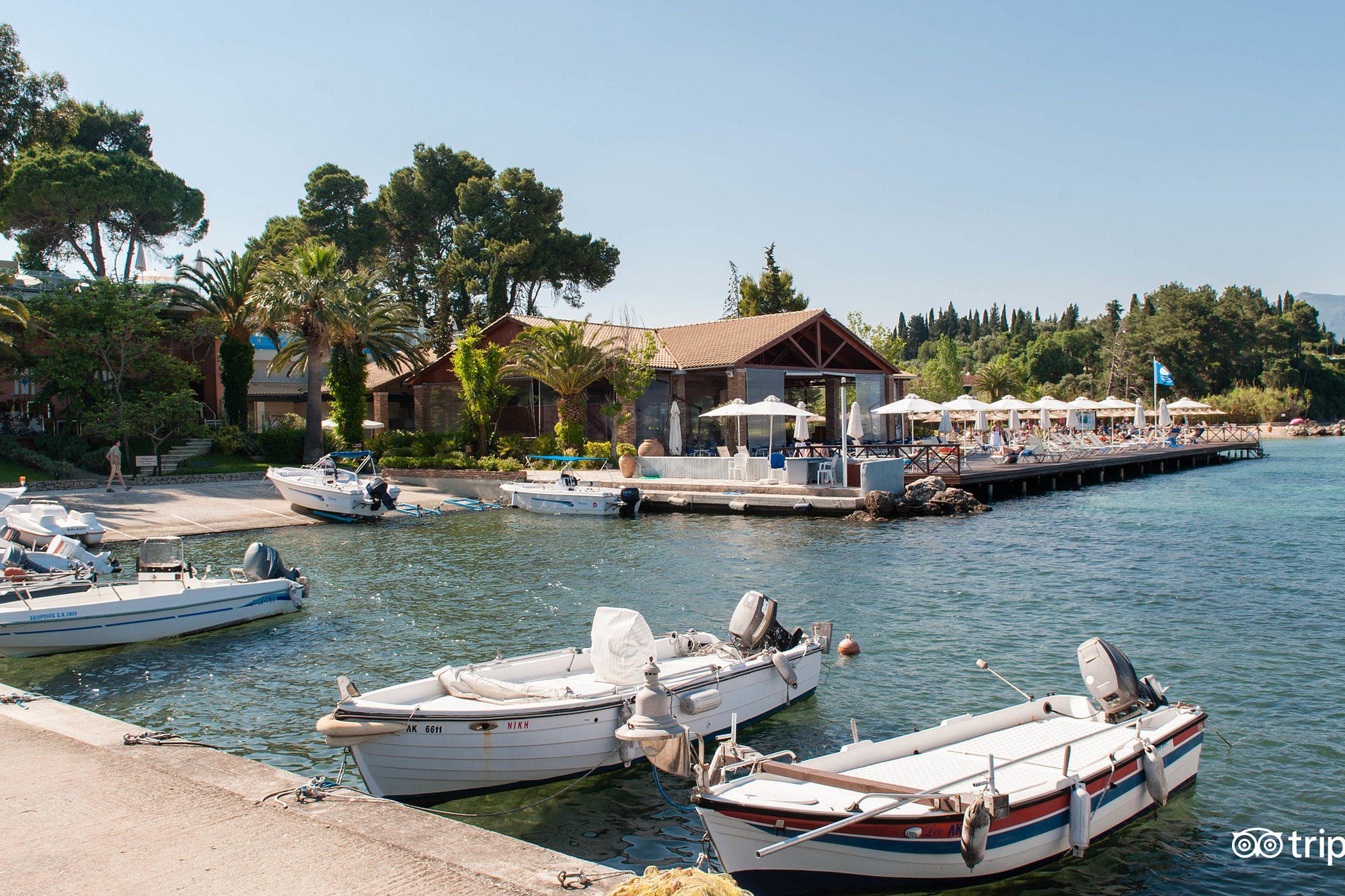 Small boats docked by a quaint waterfront house surrounded by greenery.