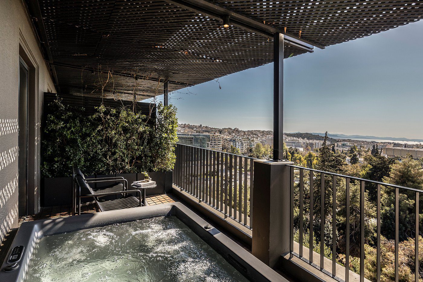A relaxing outdoor jacuzzi with city views under a shaded pergola.