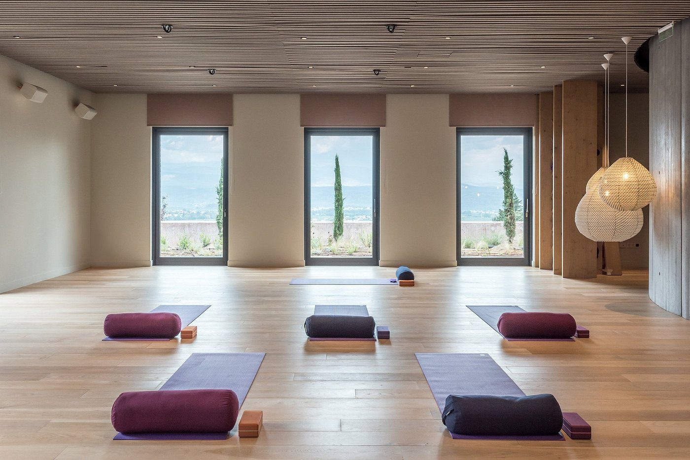 Peaceful yoga studio with cushions and a scenic view through large windows.