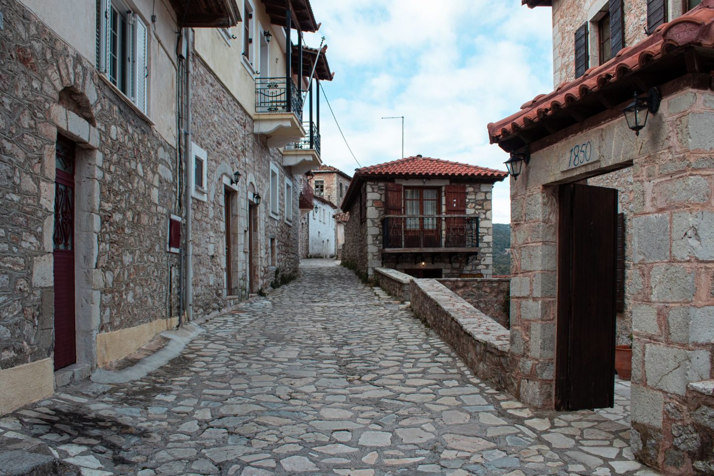 Quiet cobblestone street with stone buildings and wooden balconies.