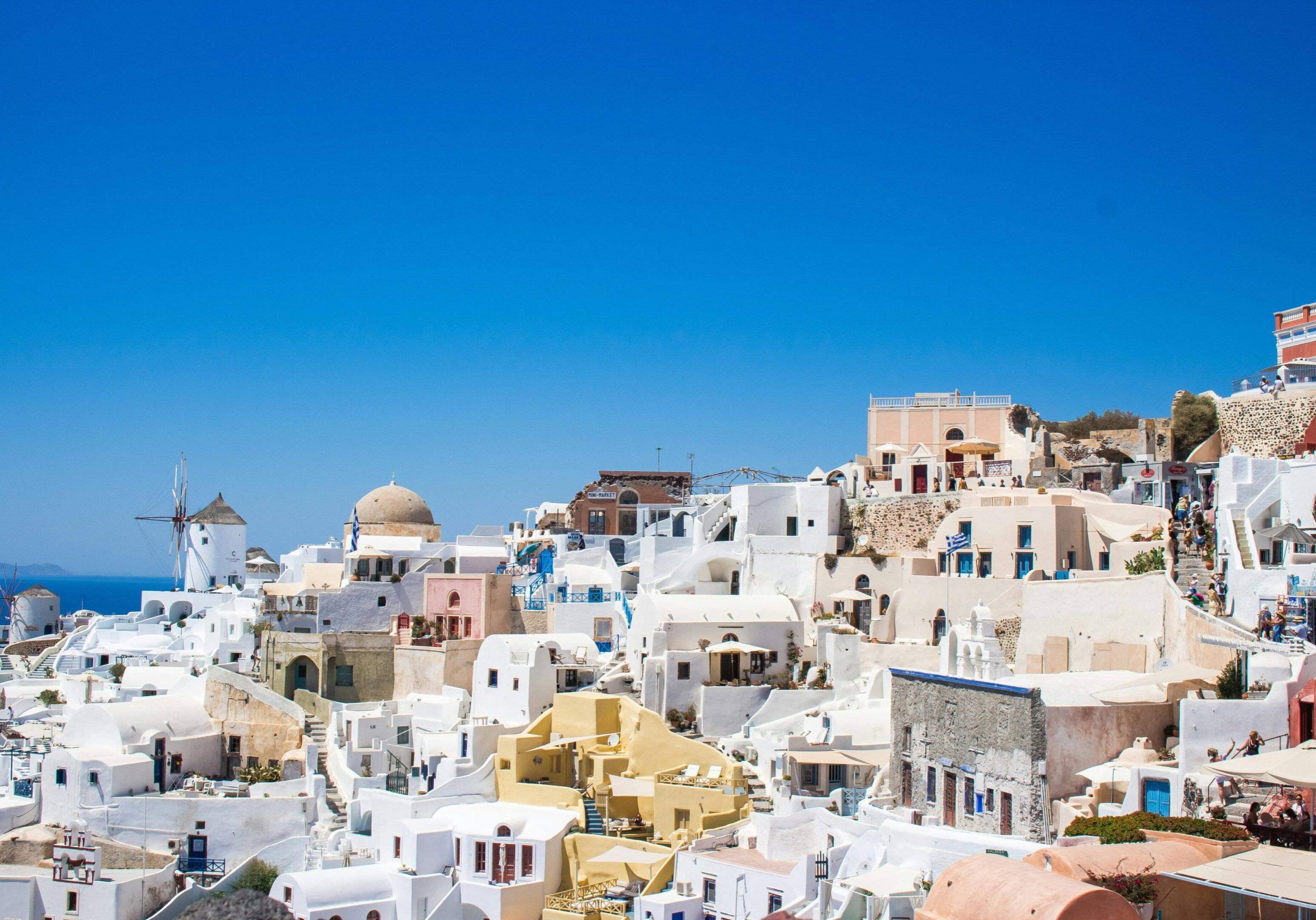 Scenic view of whitewashed buildings with blue domes under a clear blue sky.